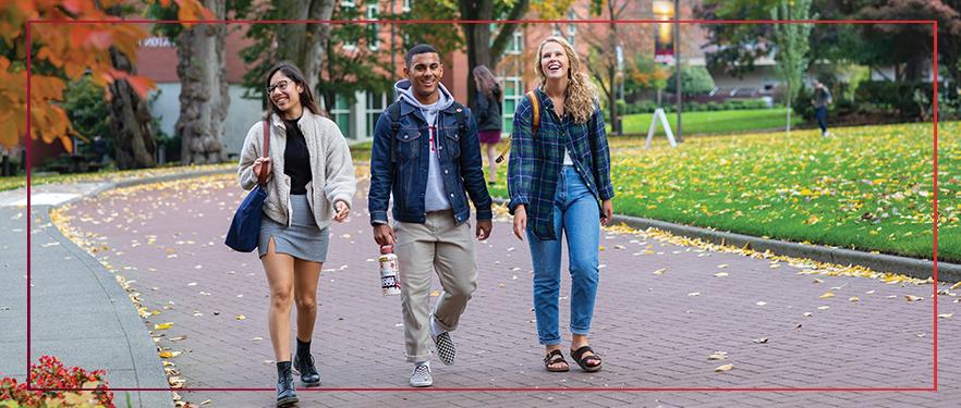 One male and two female SPU students walking in Tiffany Loop in the fall.