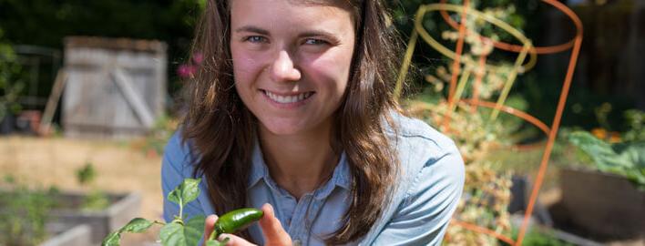 girl smiles with pepper plant