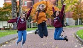 Three SPU student jump and laugh while in Tiffany Loop