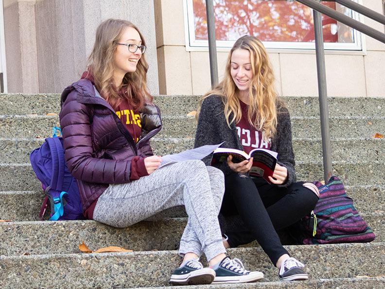 Two SPU students sit on the steps of the theater, talking